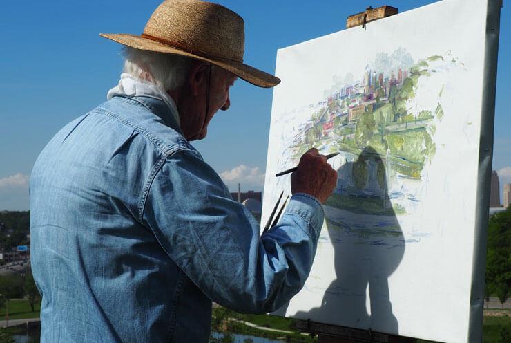 A senior is outdoors and paints a picture